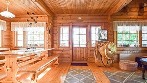 A wooden cabin interior with a dining table, benches, a television, and a large carved wooden sculpture. - Linnunlaulu by Interhome (Lapinlahti)