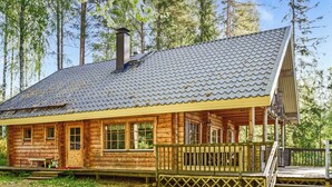 A log cabin with a porch, a chimney, and a staircase leading to a deck. - Linnunlaulu by Interhome (Lapinlahti)