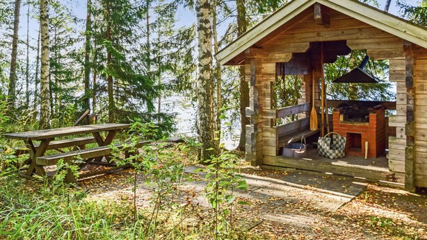 A rustic cabin with a wooden exterior, a chimney, and a small porch. - Linnunlaulu by Interhome (Lapinlahti)