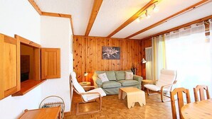 Ein gemütliches Wohnzimmer mit Holzwänden, einem grünen Sofa, einem Holzesstisch und einem Holzstuhl.