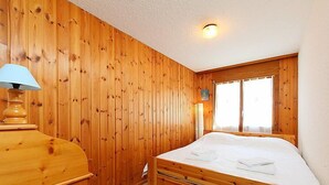 Ein Zimmer mit Holzboden, einem Bett, einem Schreibtisch und einem Fenster.