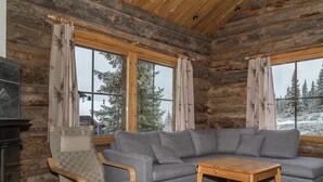 A log cabin interior with a gray sofa, wooden chair, and a small wooden table.