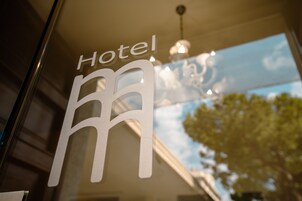 A hotel sign with a modern design, featuring a stylized 'm' and the word 'Hotel' above it.