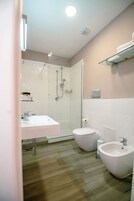 A modern bathroom with a glass shower enclosure, a white sink, a bidet, and a toilet.