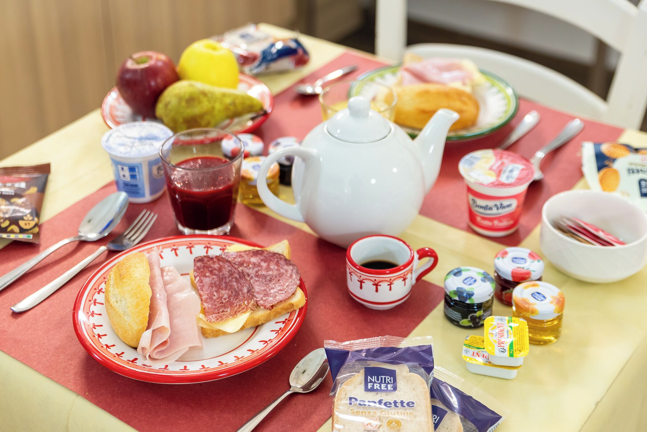 Et morgenbord med forskellige spiser, en tepotte og en kop kaffe.