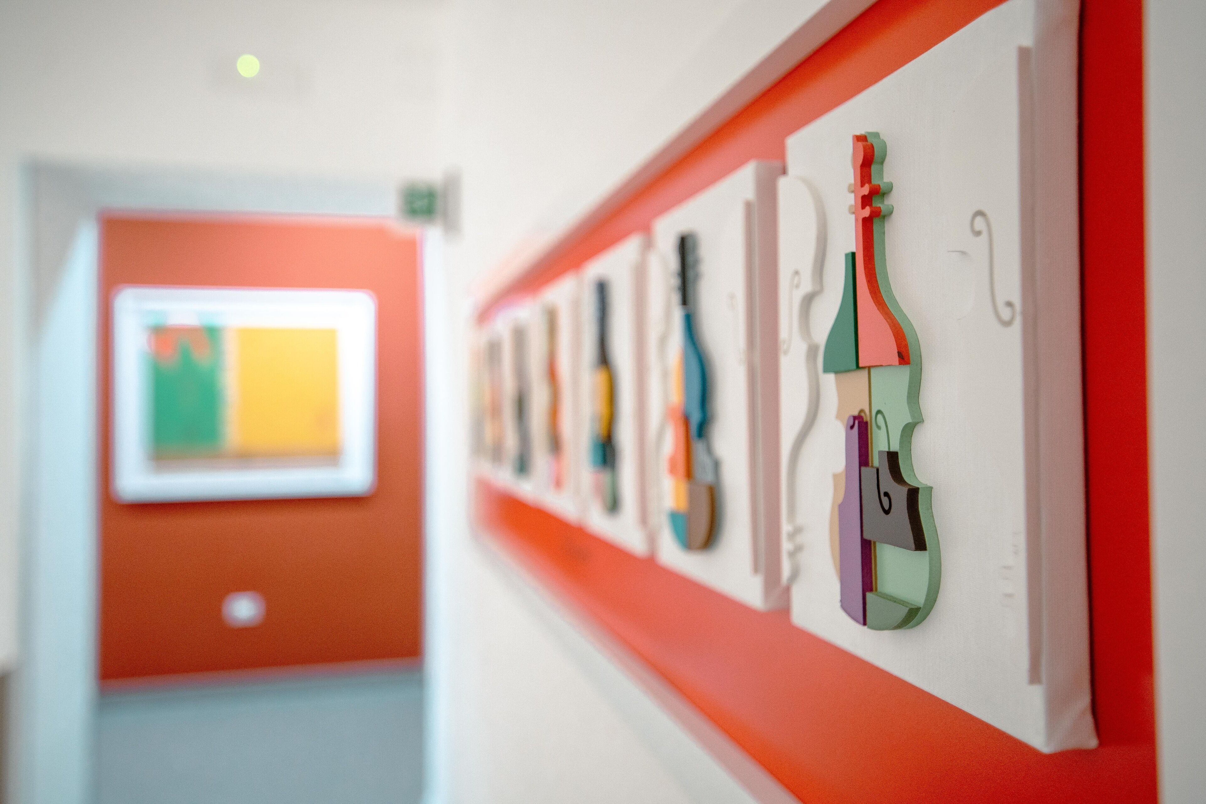 Un pasillo decorado con varias obras de arte abstractas y coloridas.