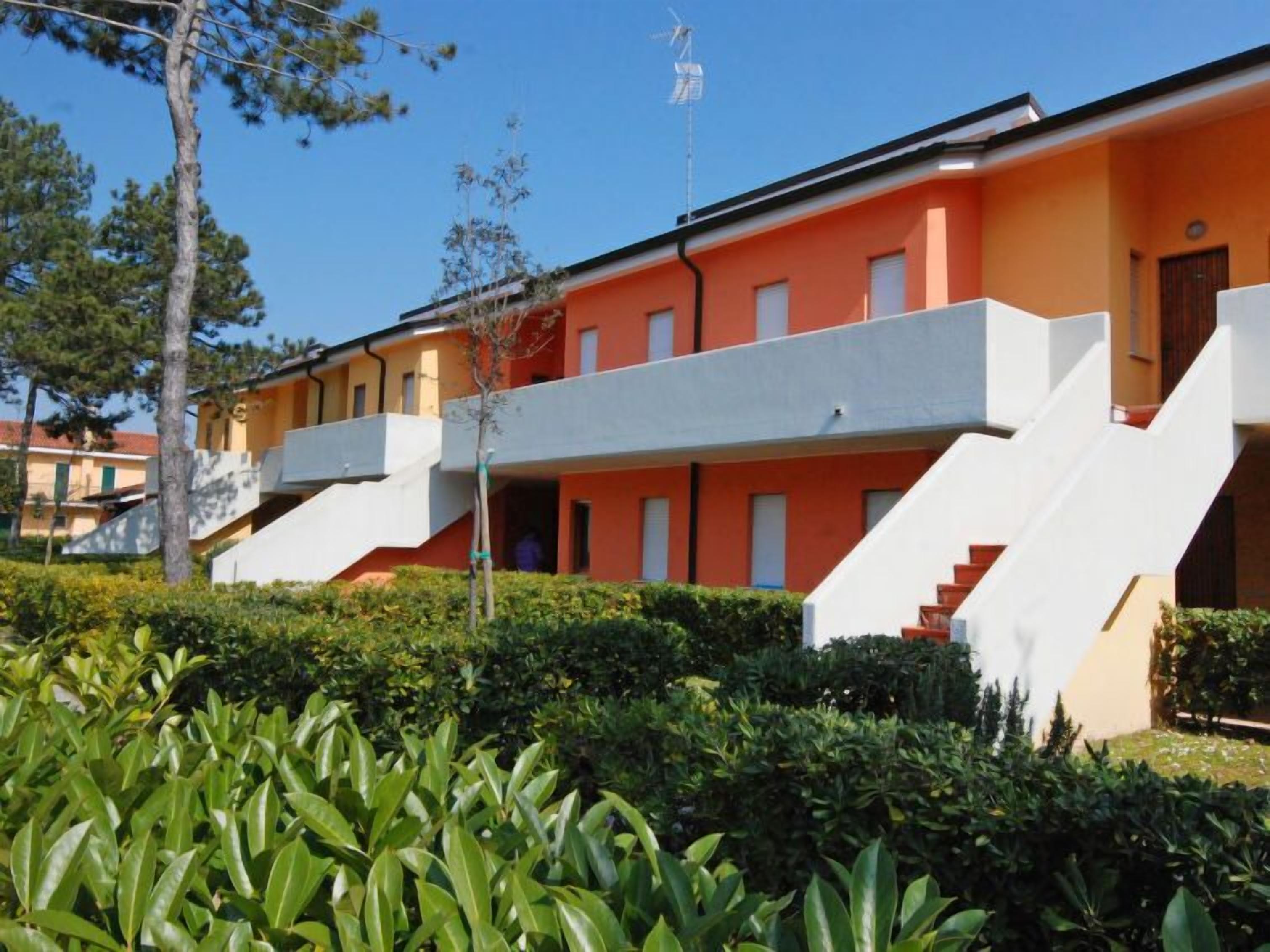 A modern building with a flat roof, a staircase leading to a balcony, and a flagpole.