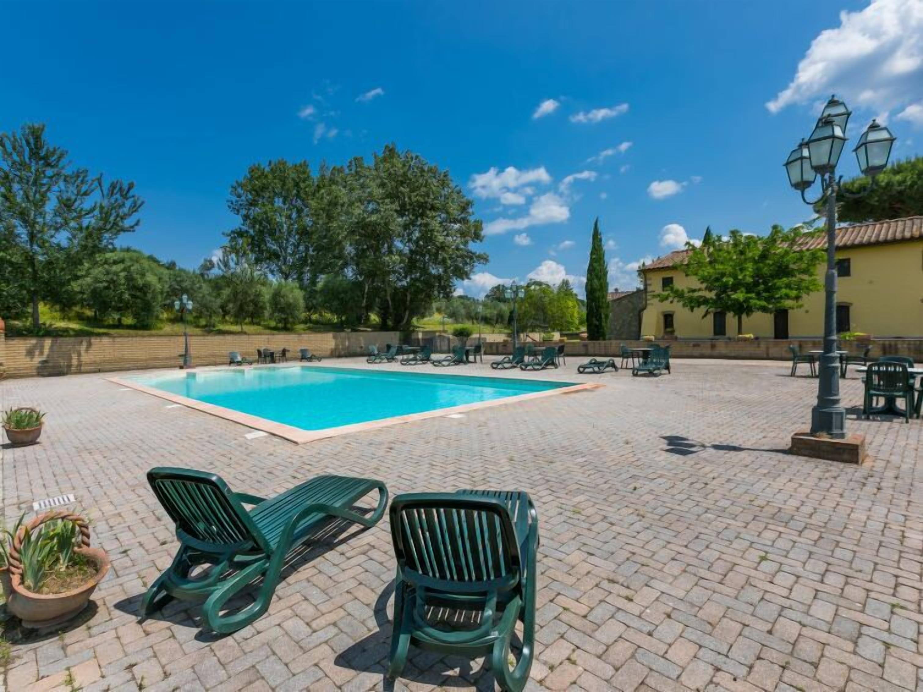 Une piscine avec des chaises longues et une terrasse dallée.