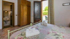 A bedroom with a bed, a wooden wardrobe, a bathroom, and a view of the outdoors. - Montereggi by Interhome (Vinci)