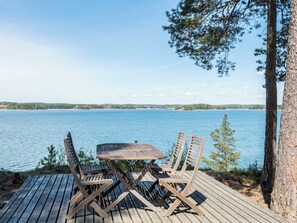 A wooden deck with a table and chairs overlooking a calm lake, surrounded by trees. - Merimetso by Interhome (Sauvo)