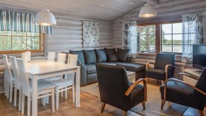 A cozy cabin interior with a dining table, chairs, a sofa, and a TV. - Merimetso by Interhome (Sauvo)