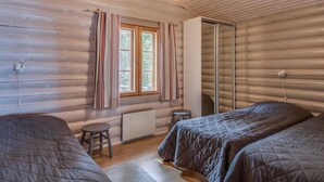 A cozy cabin room with two beds, a small stool, a radiator, and a window with curtains. - Merimetso by Interhome (Sauvo)