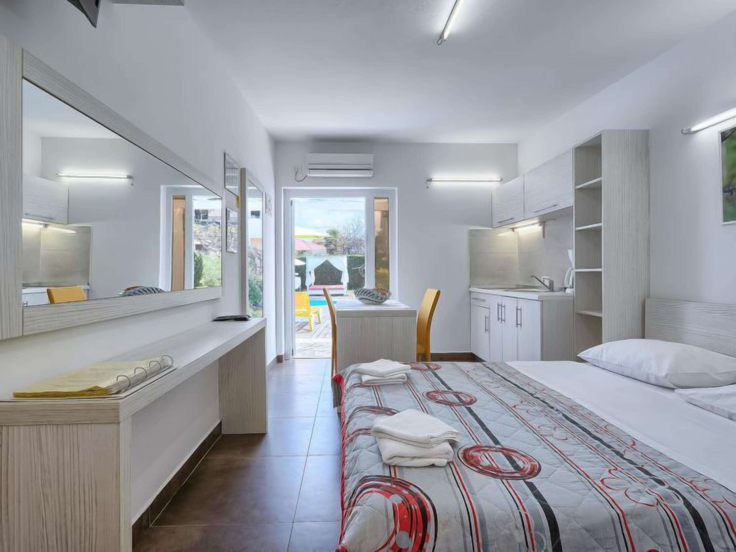 A modern hotel room with a large bed, a desk, and a view of the outside.