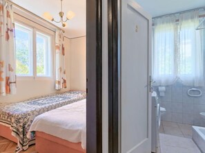 A bedroom with a bed, a window with curtains, and a chandelier.