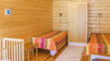 A small, cozy room with wooden walls and a single bed with a colorful bedspread.