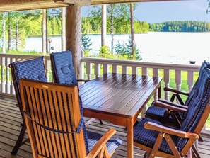A wooden deck with a table and chairs, overlooking a lake. - Villa hermanni by Interhome (Pieksämäki)