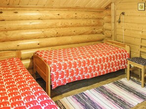 A cabin with two wooden beds, a small table, and a patterned rug. - Villa hermanni by Interhome (Pieksämäki)
