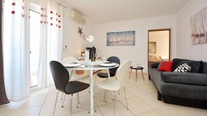 Una sala de estar moderna con comedor, un sofá gris y un cuadro en la pared.