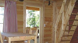 Un intérieur en bois avec une table et des chaises, un rideau à rayures et un escalier.