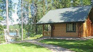 Une cabane en rondins avec un porche, une fenêtre et une vue sur un lac.