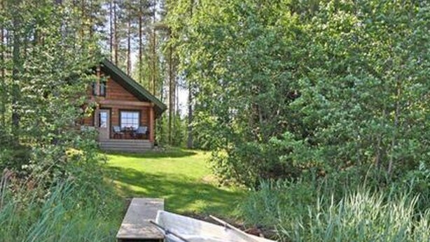 Une cabane avec un quai qui s’avance dans une zone boisée.