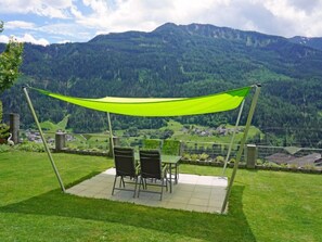 A patio with a table and chairs, a green canopy, and a view of a mountainous landscape. - Muehlbach by Interhome (Fliess/Landeck/Tirol West)