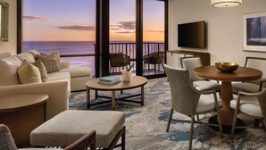 Ein modernes Wohnzimmer mit Meerblick, eine Couch, ein Couchtisch und ein Essbereich mit Stühlen.