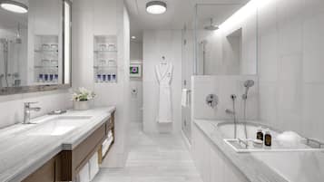 A modern bathroom with two sinks, a bathtub, and a glass-enclosed shower.