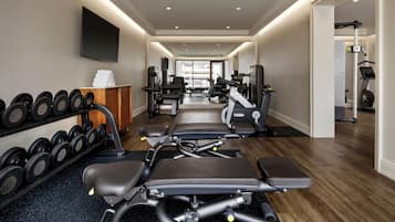 A gym with exercise equipment, dumbbells, and a treadmill.