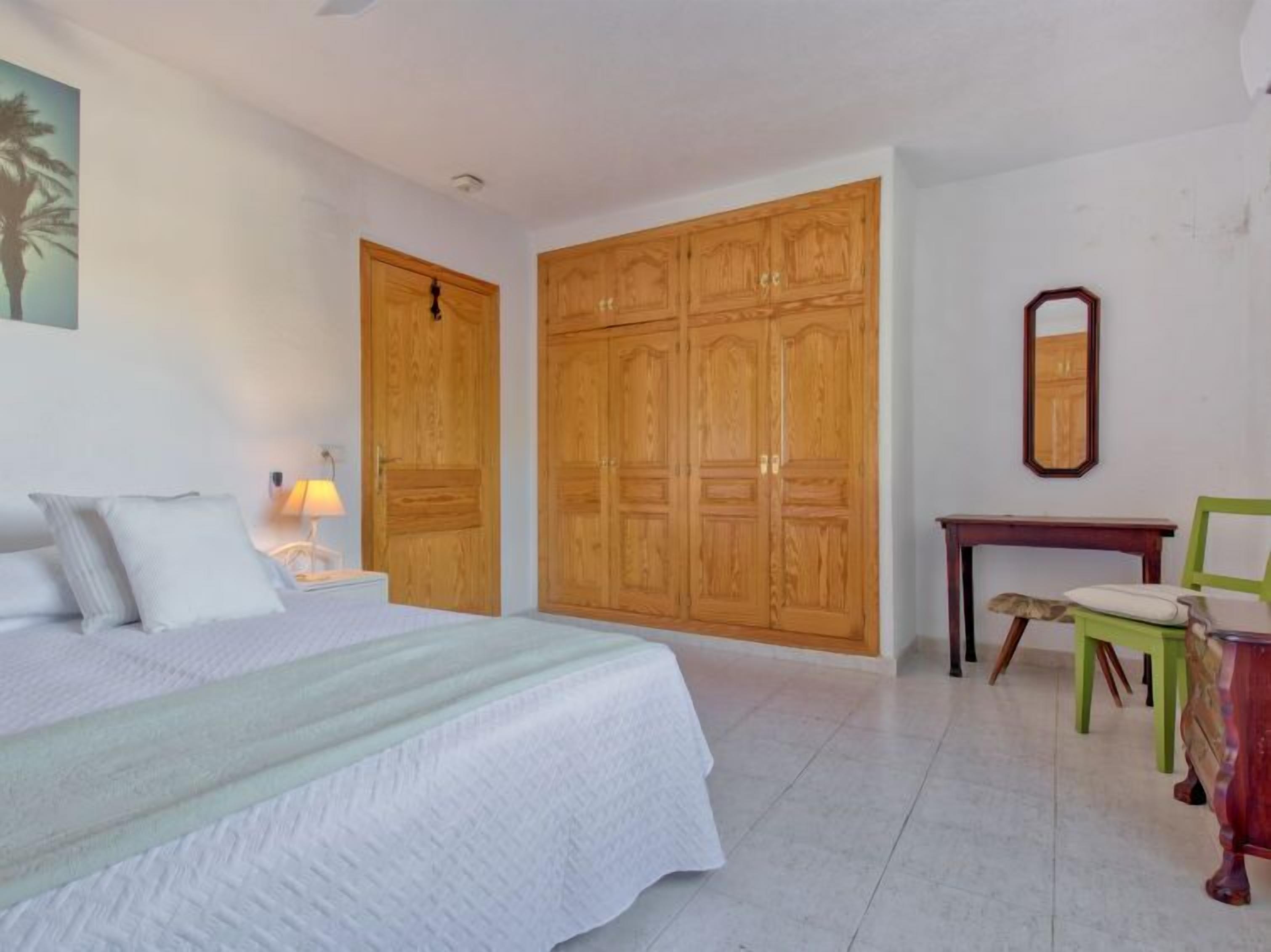 Un dormitorio con una cama, un armario de madera, un escritorio y una silla.