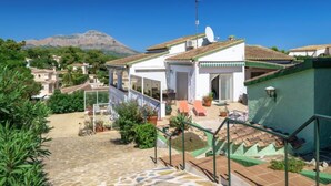 A white building with a tiled roof, a satellite dish, and a green staircase leading to a covered patio area. - Vacation home Bosque by Interhome (Jávea)