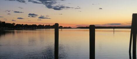 Un lago tranquilo al atardecer con postes de madera en primer plano.