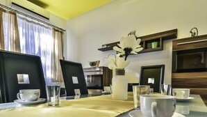 A hotel room with a dining table set for two, a vase with white flowers, a flat-screen TV, and a modern decor style. - Apartment Anić by Interhome (Novigrad (Zadar))