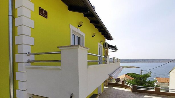 A yellow building with a balcony, a stone-tiled patio, and a view of the sea. - Apartment Anić by Interhome (Novigrad (Zadar))