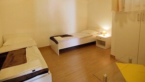 A small, single-bed room with a wooden floor, a bedside table with a lamp, and a wardrobe. - Apartment Anić by Interhome (Novigrad (Zadar))