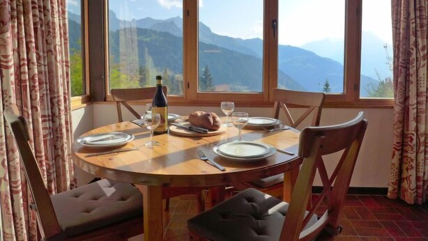 A dining table with chairs, a bottle of wine, and plates set for a meal. - La Vire D'Aufalle 14 Inférieur by Interhome (Alpe des Chaux)