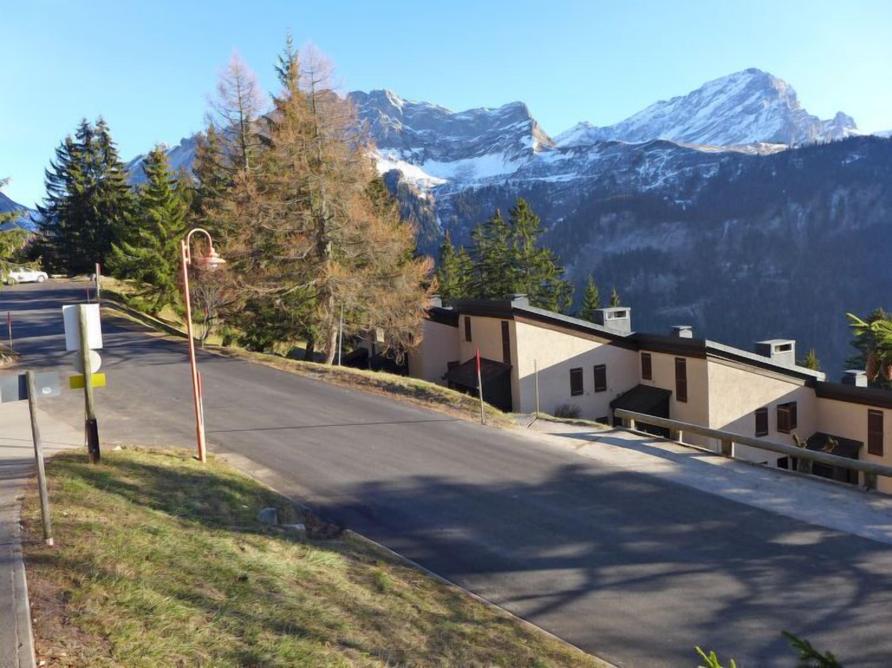 A road leading to a building complex with a mountainous backdrop.