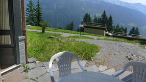 A terrace with a view of mountains, a chair, and a table. - La Vire D'Aufalle 14 Inférieur by Interhome (Alpe des Chaux)