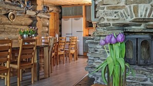 A rustic dining area with wooden furniture and a stone fireplace.