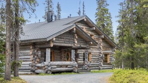 A log cabin with a steeply pitched roof, wooden exterior, and a front porch.