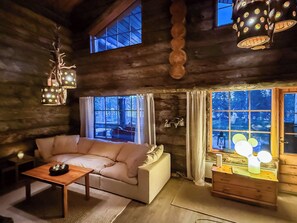 A cozy log cabin interior with a sofa, a table, and a lamp.