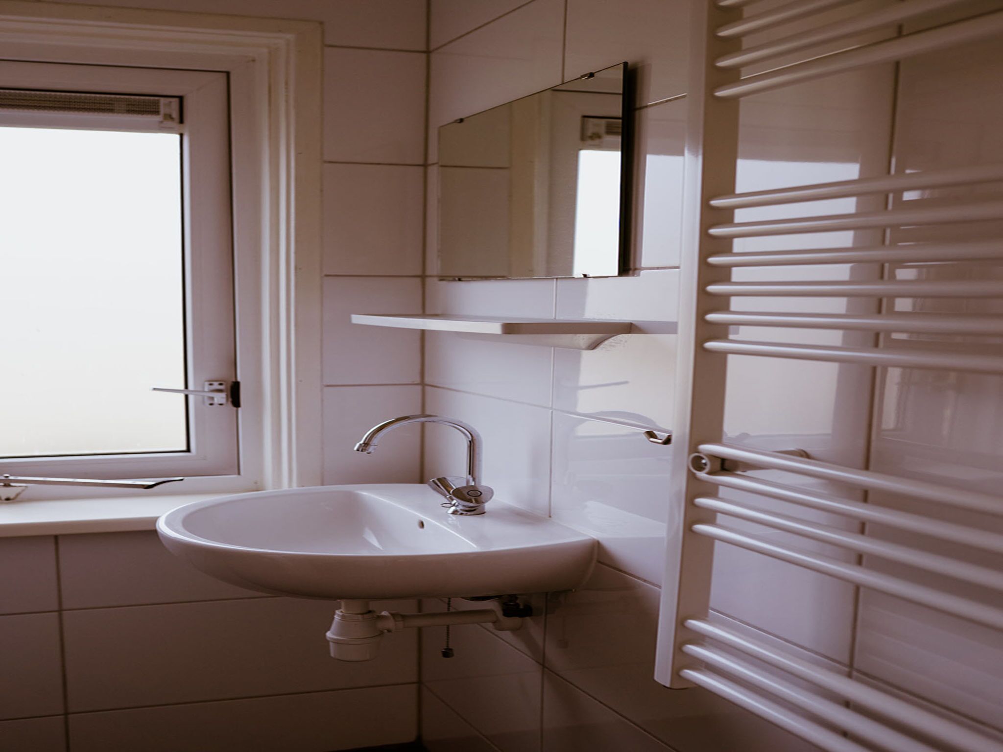 Une salle de bain avec un lavabo blanc, un miroir au-dessus et un porte-serviettes.