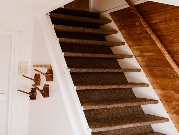 A staircase with carpeted steps leading to a wooden floor.