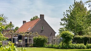 A traditional house with a sloped roof, a visible chimney, and a well-maintained lawn.