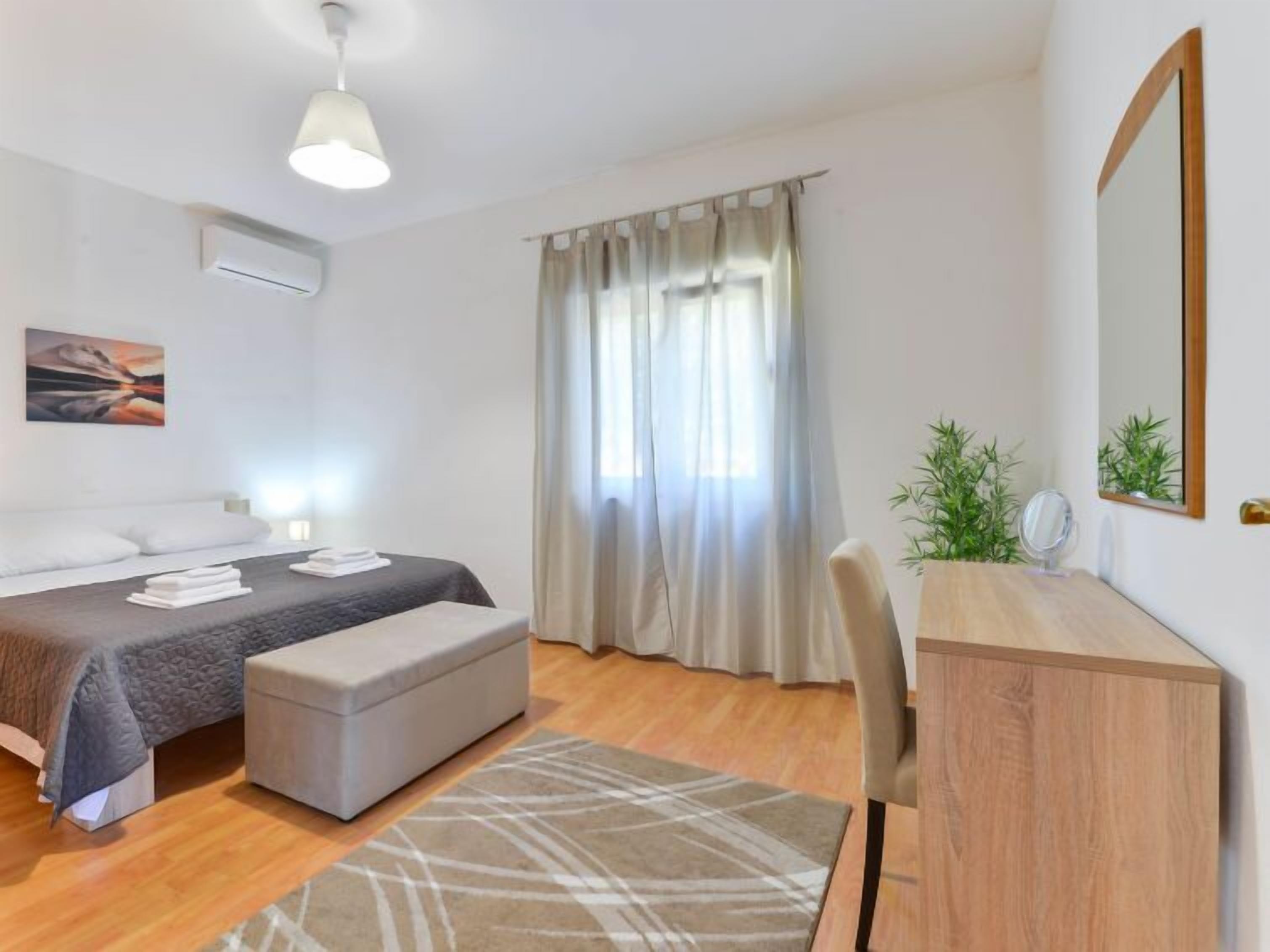 A modern bedroom with a bed, bedside table, and a desk with a mirror.