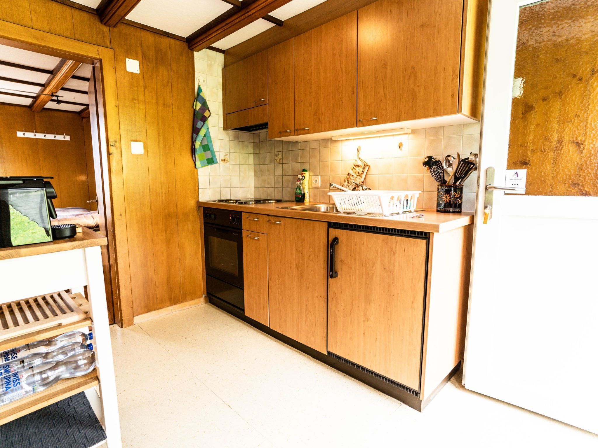 A compact kitchen with wooden cabinets, a built-in oven, and a sink.