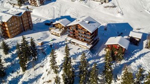 Un resort cubierto de nieve con varias edificaciones de madera, pistas de esquí y pinos.