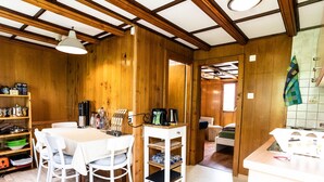 Un interior de madera con una mesa de comedor, sillas, una zona de cocina y un área de descanso.