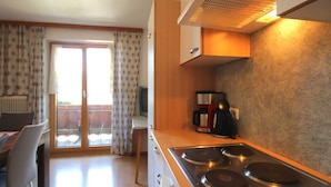 A compact kitchen with a stove, a coffee maker, and a television. - Jägerhof by Interhome (Schwaz)