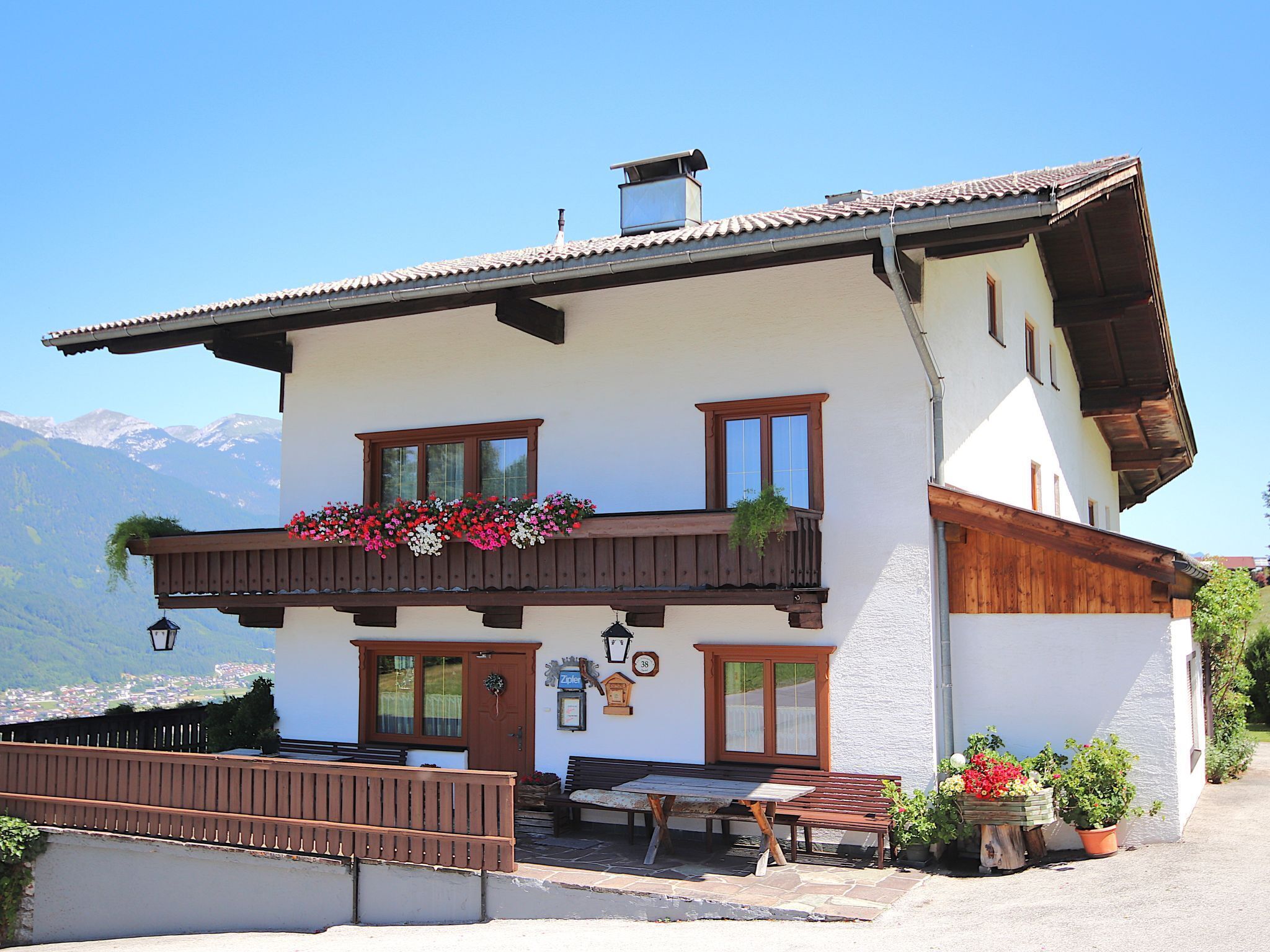 A two-story building with a balcony, a wooden bench, and a table outside.